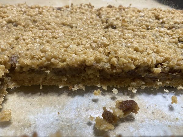 Close-up of a homemade date crumble bar with layers of oats and sweet date filling