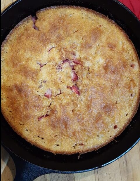 Strawberry cream cheese cobbler baked in a cast iron skillet with a golden crust and sweet strawberries peeking through