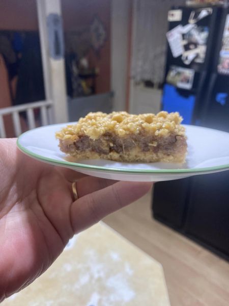 A slice of homemade date crumble on a white plate, showing its layered texture.