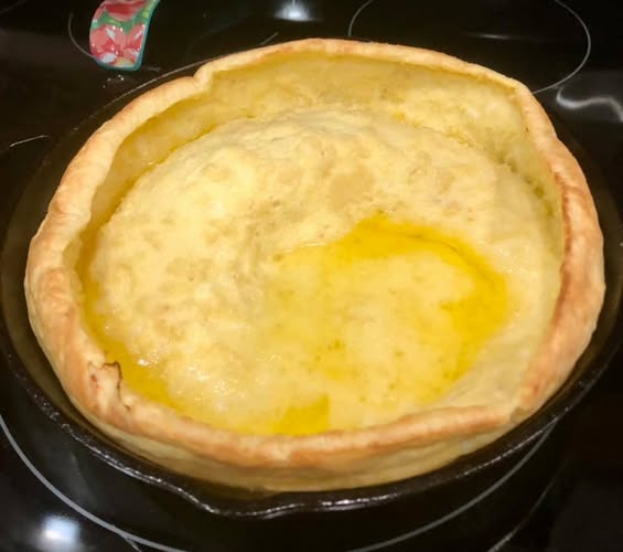Dutch baby pancake in cast‑iron skillet – puffy and golden"