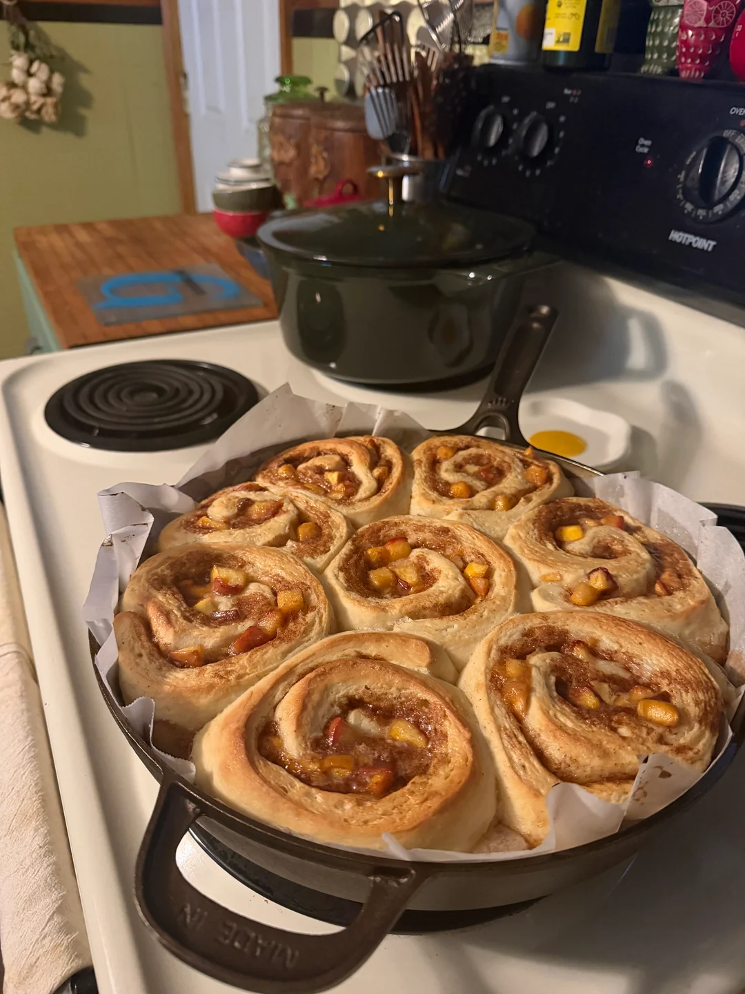 Ten unbaked peach cinnamon rolls resting snugly inside a parchment-lined 12-inch cast iron skillet.