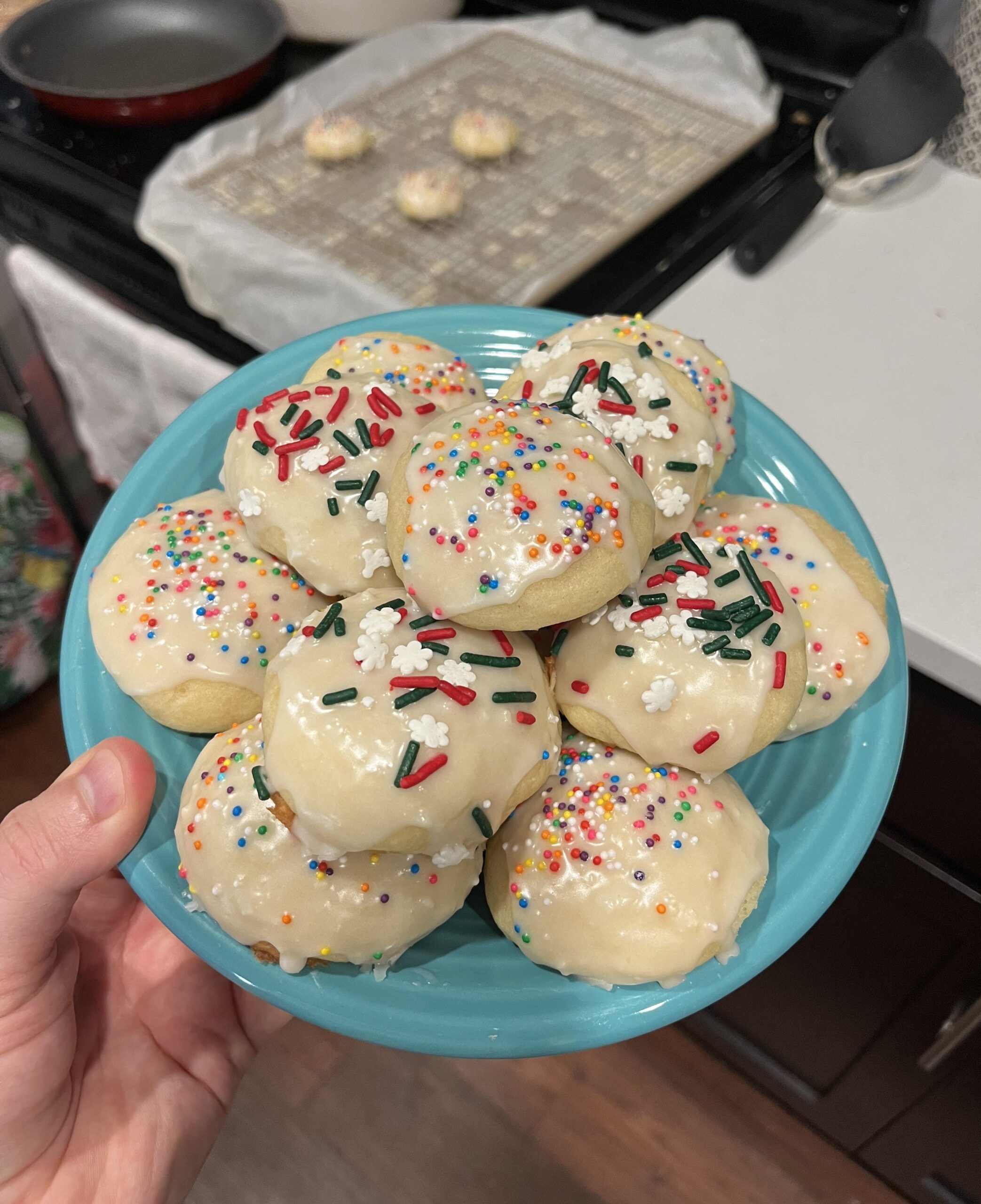Soft Italian ricotta Christmas cookies topped with white almond glaze and festive red and green sprinkles on a vintage holiday cookie platter