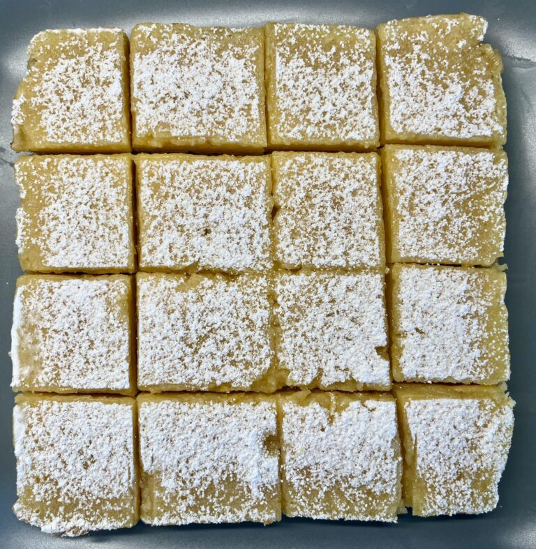 Soft yellow three-ingredient lemon bars dusted with powdered sugar in a white baking dish, with a fork lifting one square