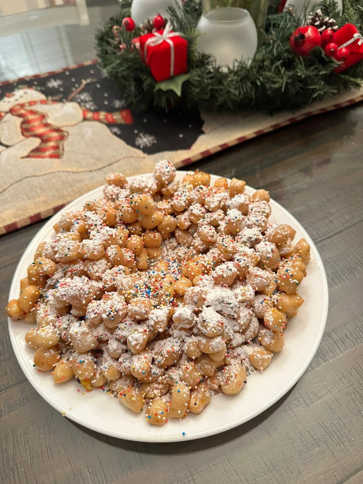 Traditional Italian Christmas struffoli made with golden fried dough balls coated in honey and decorated with colorful sprinkles.