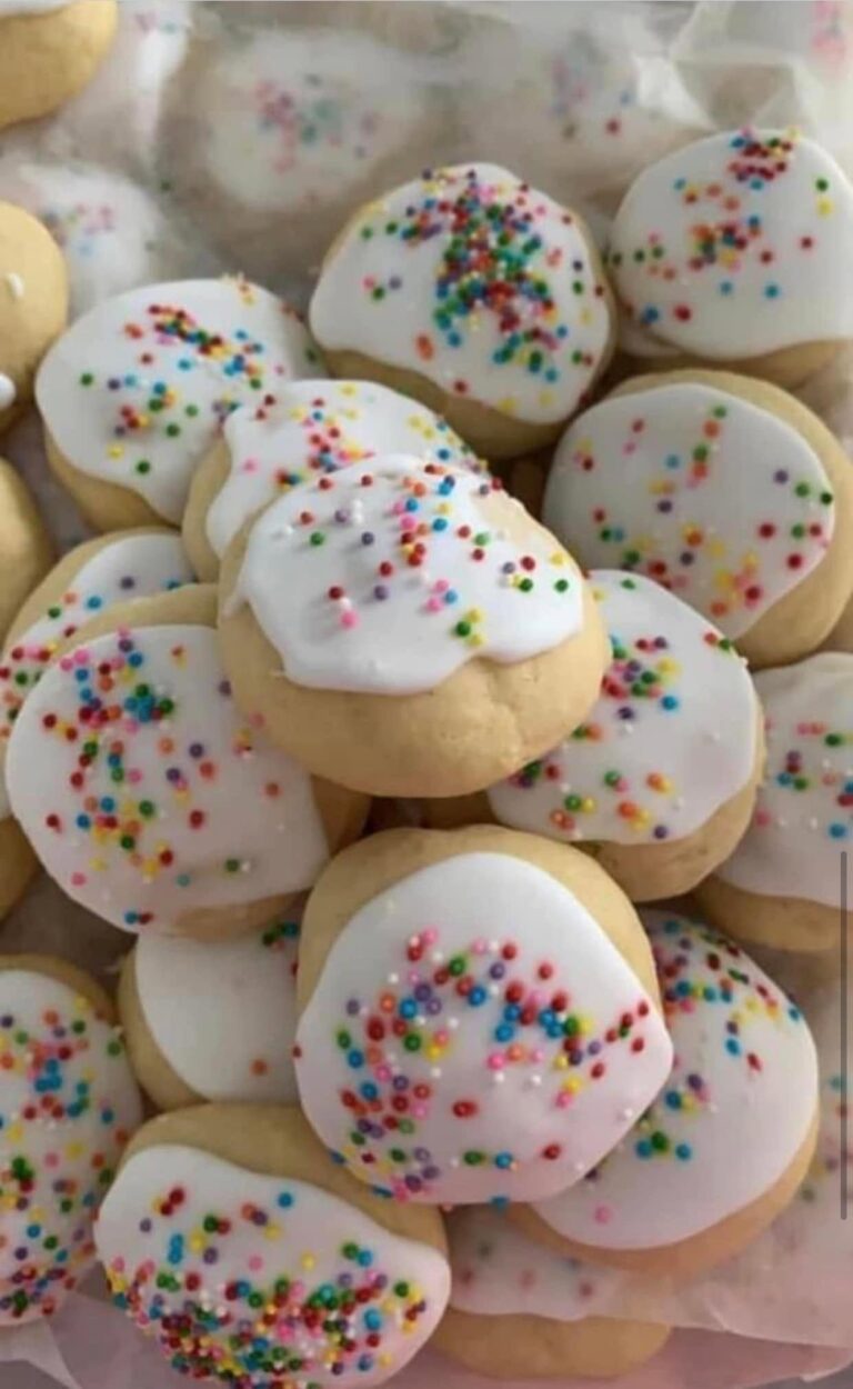Homemade old-fashioned Italian anisette cookies with thick white icing and colorful rainbow sprinkles.
