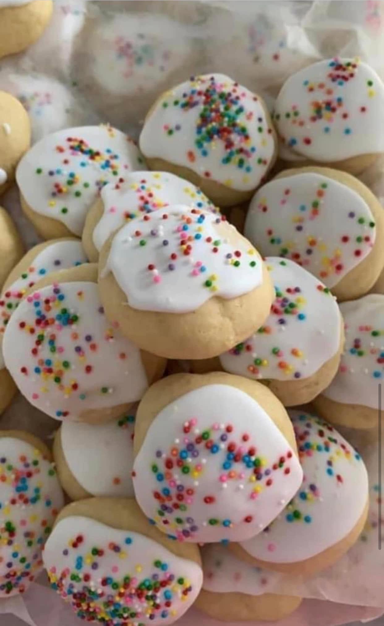 Homemade old-fashioned Italian anisette cookies with thick white icing and colorful rainbow sprinkles.
