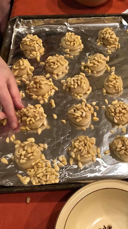 unbaked pignoli cookies covered in pine nuts on the baking sheet.