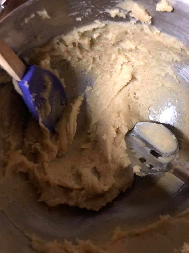 the sticky almond paste dough being mixed in a large metal bowl
