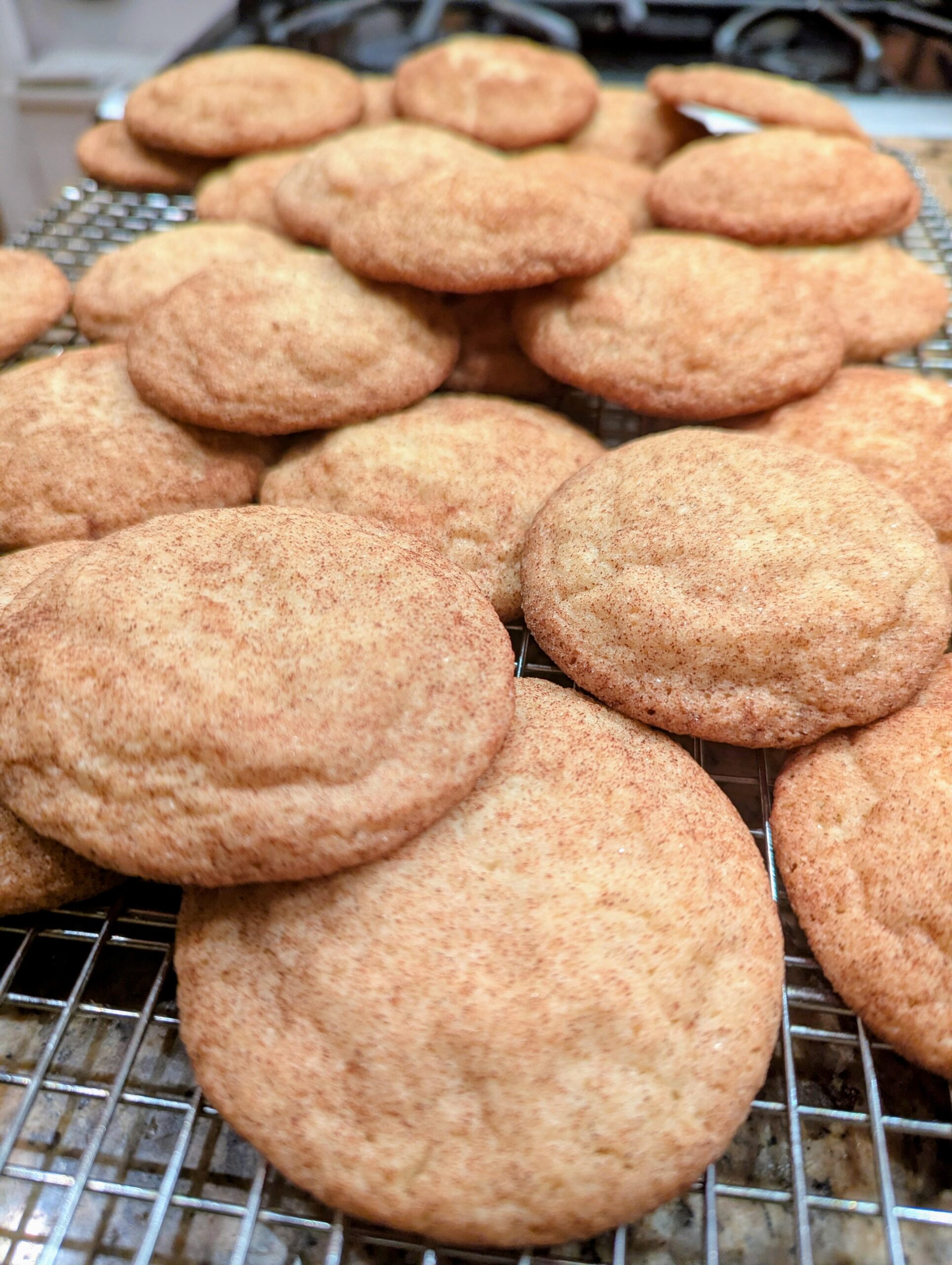 Homemade soft and chewy snickerdoodle cookies with crinkled tops and cinnamon-sugar coating on a baking sheet.
