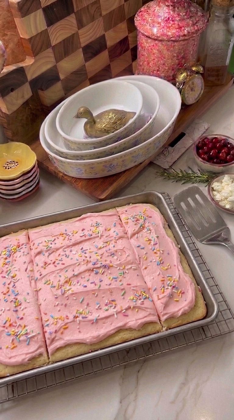 Soft homemade sugar cookie bars topped with thick pink buttercream frosting in a rectangular baking pan.