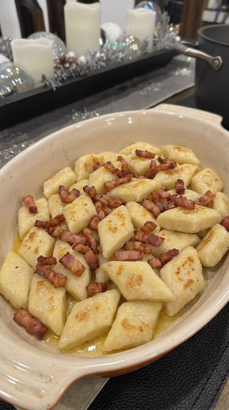 Polish kopytka dumplings with crispy bacon in a cream-colored serving dish