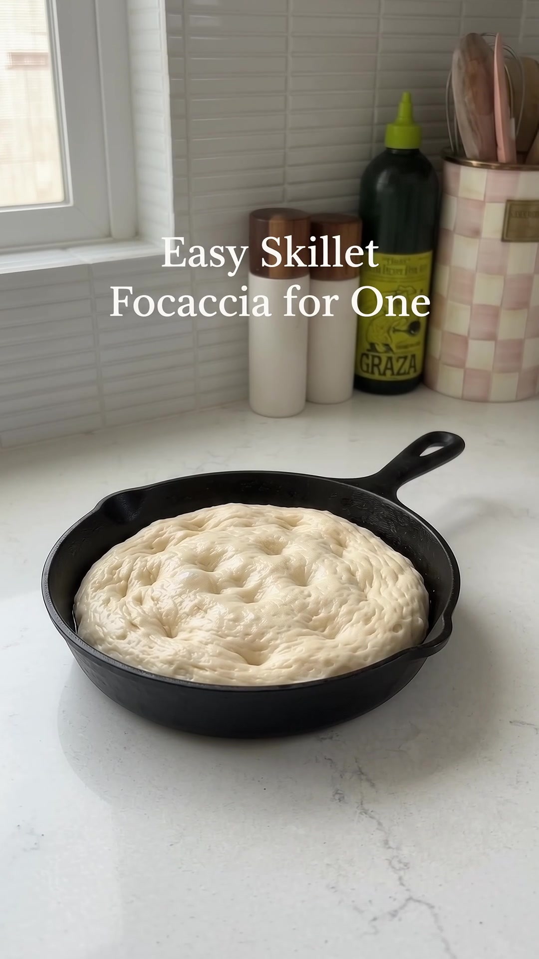Soft risen focaccia dough resting in a small cast iron skillet before baking.