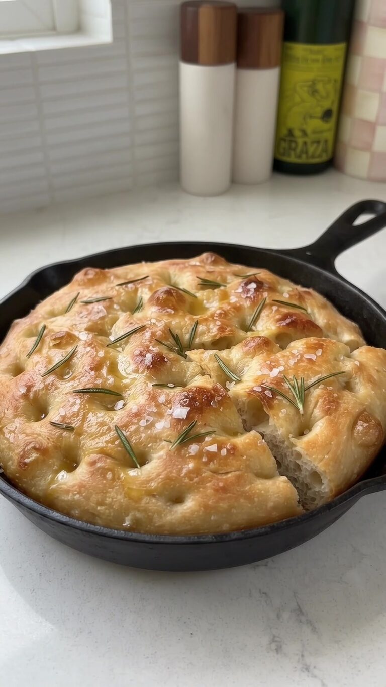 Golden homemade skillet focaccia with rosemary and flaky sea salt baked in a black cast iron skillet.