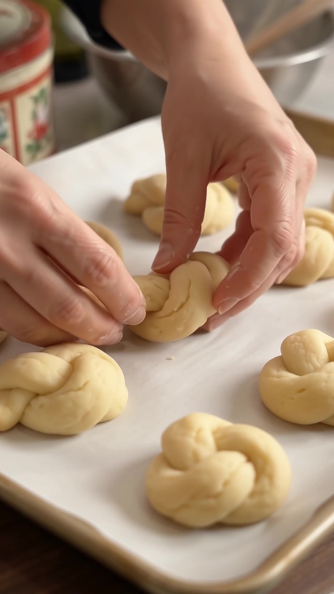 Unbaked Italian lemon knot cookies arranged on a parchment-lined baking sheet.