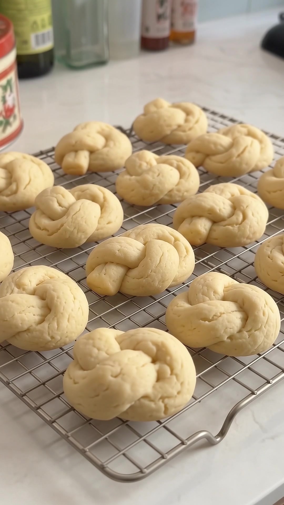 Freshly baked Italian lemon knot cookies cooling on a wire rack before glazing.