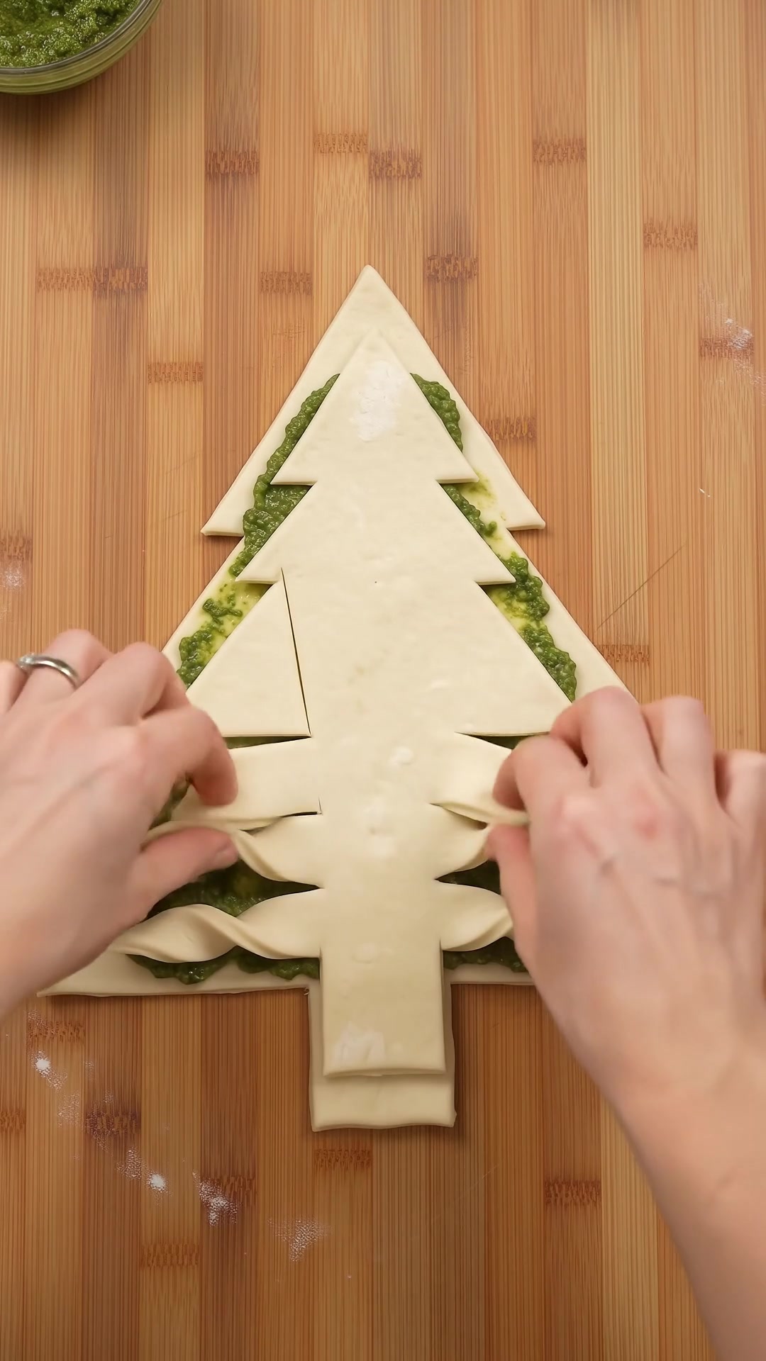 Unbaked puff pastry Christmas tree with pesto filling and twisted branches ready for the oven.