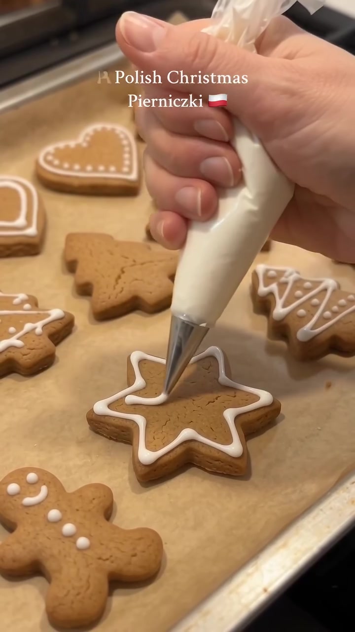 white icing being piped onto a star-shaped gingerbread cookie.