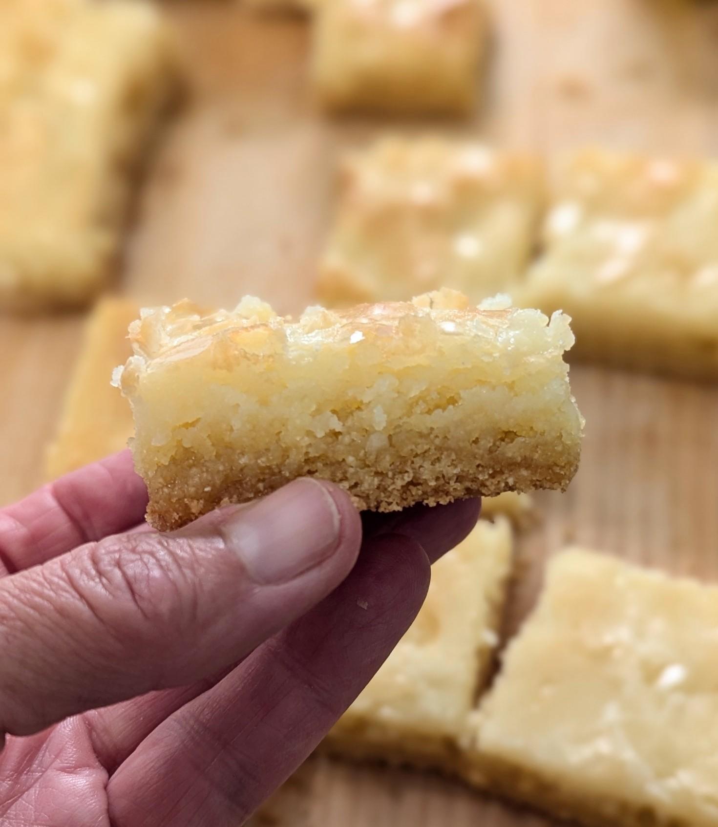 the close-up of one chess bar held between the fingers, showing the gooey filling and buttery crust.