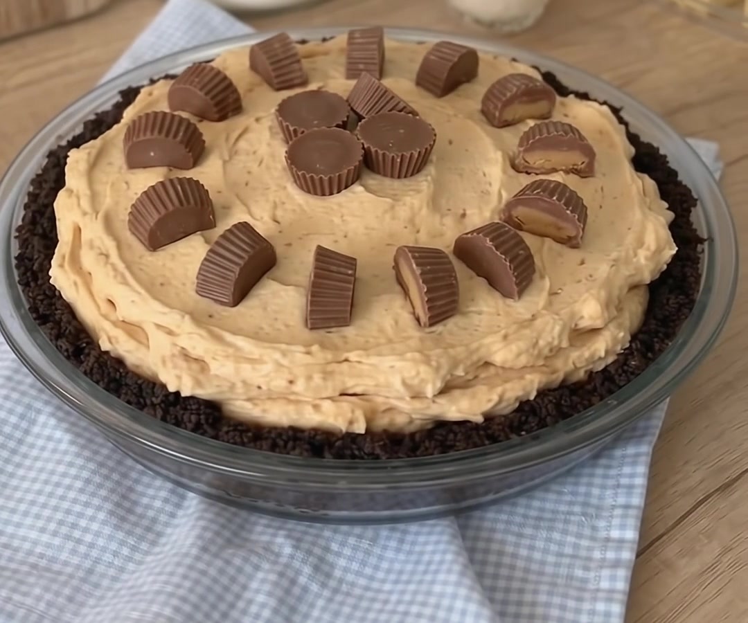 Homemade no-bake peanut butter pie in an Oreo crust decorated with chocolate peanut butter cups.